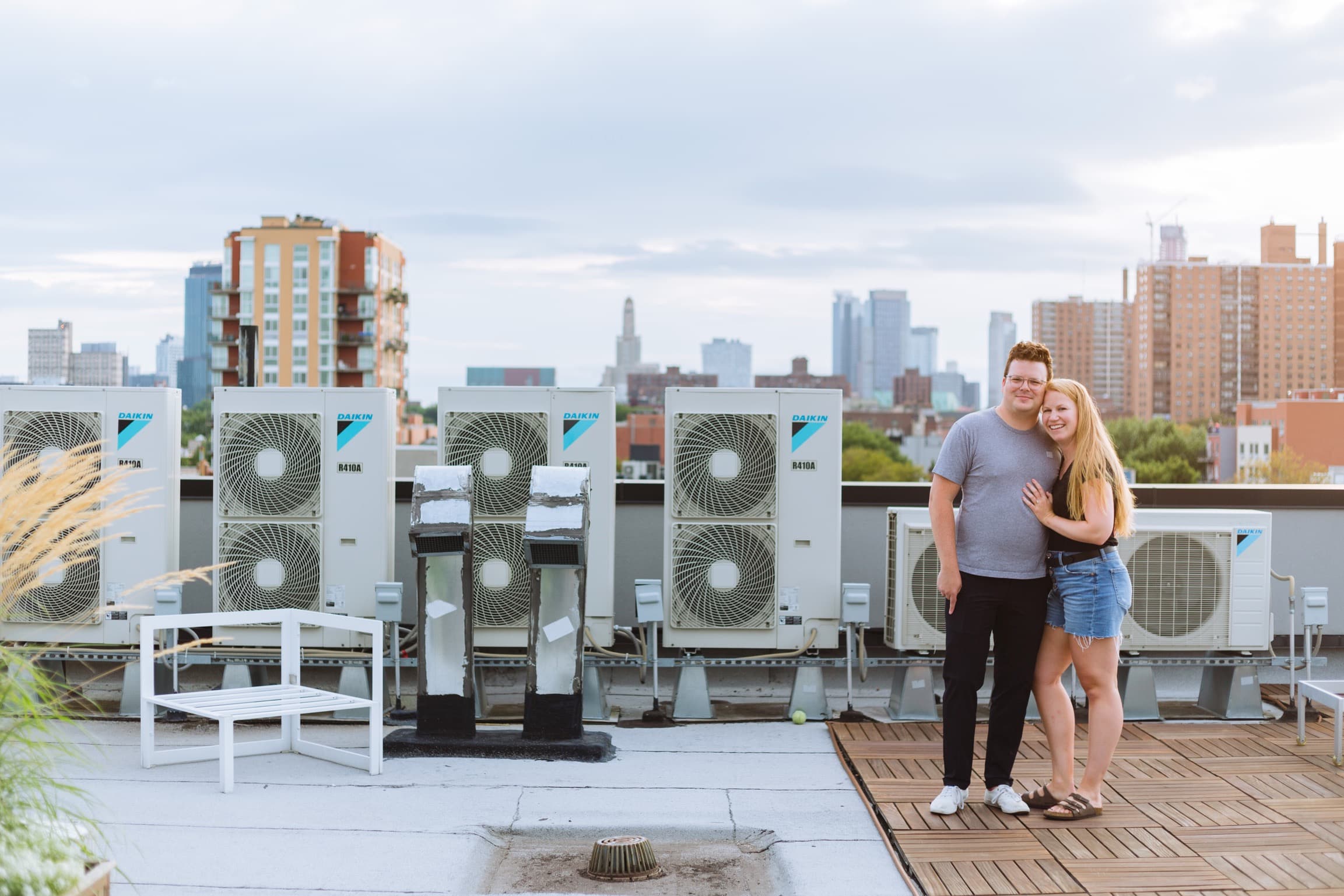 Ben and Michelle standing next to air conditioners on the roof of their old Brooklyn apartment after getting engaged